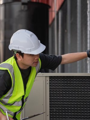Engineers are inspecting the cooling system of an air conditioning unit in industrial facility.